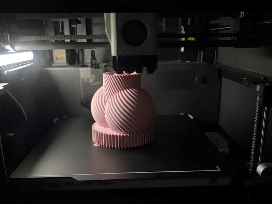 La Lampe Monsieur rose en cours d'impression sur le plateau de la Bambu Lab P1S, dans la pénombre de la machine