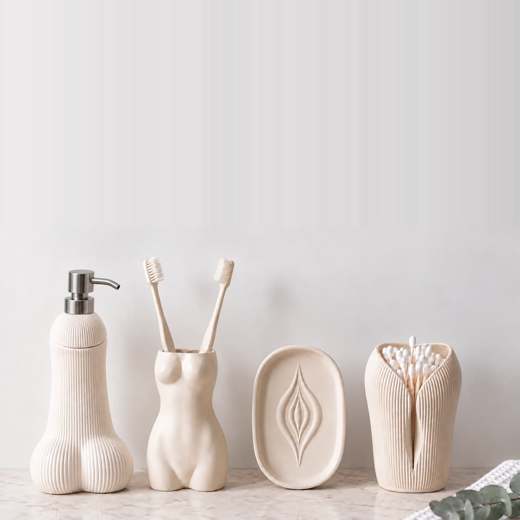 Le Nécessaire by OSER, les quatre pièces blanches alignées sur un plan de marbre : distributeur Semence strié, porte-brosses La Favorite, porte-savon L'Amande au motif creusé et porte coton-tiges L'Innocente