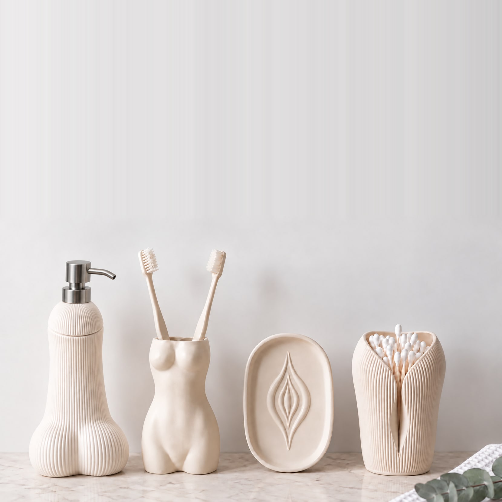 Le Nécessaire by OSER, les quatre pièces blanches alignées sur un plan de marbre : distributeur Semence strié, porte-brosses La Favorite, porte-savon L'Amande au motif creusé et porte coton-tiges L'Innocente